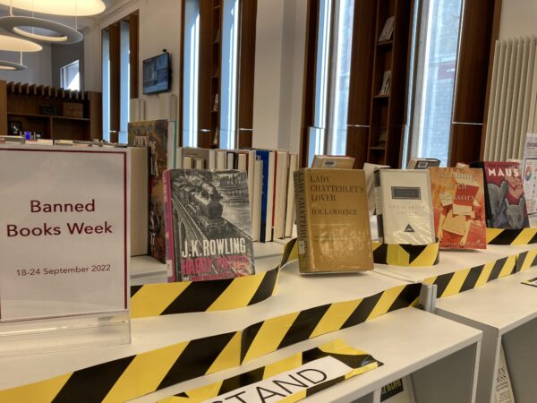 Display of books to celebrate Banned Books Week. Five books are arranged on a shelf: Harry Potter and the Sorceror's Stone, Lady Chatterley's Lover, The Scarlet Letter, Running with Scissors, and Maus